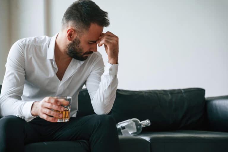 man sitting on couch drinking alcohol - the relapse cycle