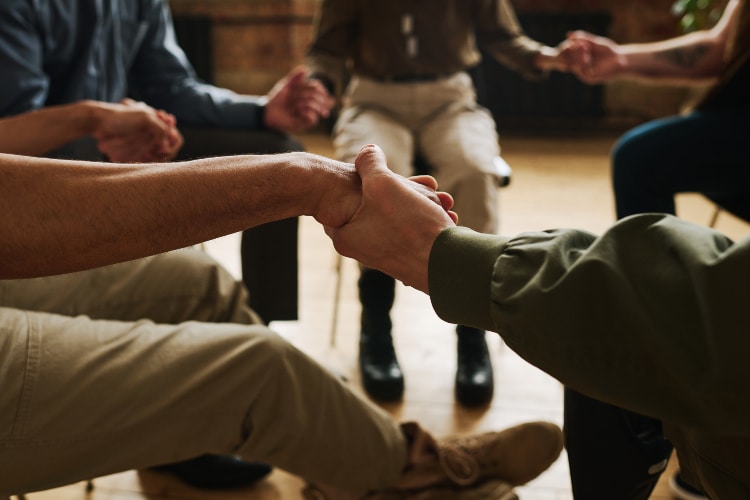 Hands of several people attending support group sitting in circle